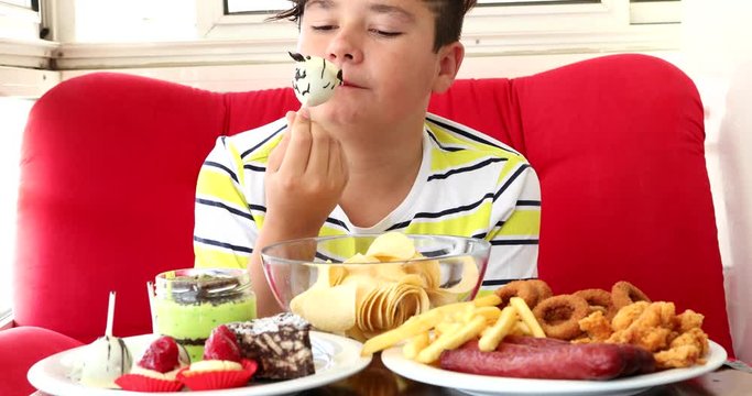 Portrait ofa caucasian teenage boy sitting at home and eating unhealthy foods.