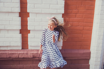 lifestyle outdoor portrait of girl in polka dot dress. Hair in the wind.