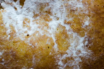 Sponge cake on the table. The texture of baking with icing sugar. Cake with white powder macro shot. The texture of the pie.