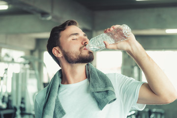 Portrait of Sport Man in Fitness Club and Drinking a Bottle of Water After Braking Exercised on...