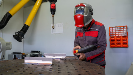 Engineers use a wireless remote control of robotic welding and robot gripping working on smart factory.