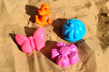 Fototapeta na wymiar Children's figures and forms insandbox on children playground. Children's game in sand for small children. Child forgot molds outdoor.
