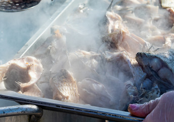 Fresh boiled river fish. Steam from pieces of fish, food on the street.