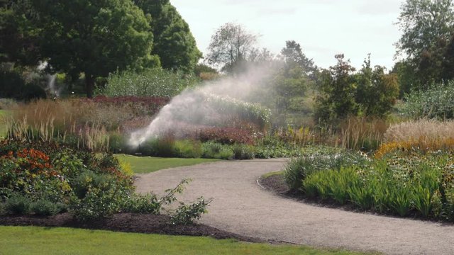 Sprinkler system watering gardens of flowers Part 2 - handheld slow motion