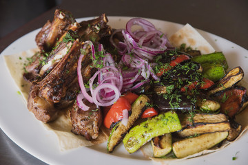 rack of lamb with grilled vegetables, decorated with sweet onion sweet onion on a white platter