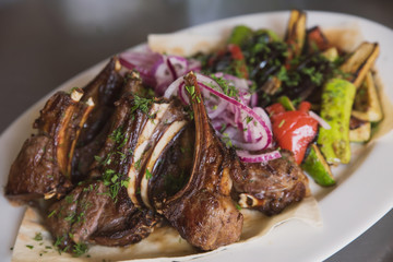 rack of lamb with grilled vegetables, decorated with sweet onion sweet onion on a white platter