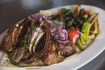 rack of lamb with grilled vegetables, decorated with sweet onion sweet onion on a white platter