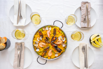 Table setting for friends meeting. Spanish paella for food friends. Top view lifestyle background.