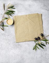 Fototapeta na wymiar Food background with linen napkin, olive tree branch, olive oil on concrete background