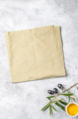 Food background with linen napkin, olive tree branch, olive oil on concrete background