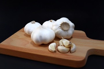 top view organic bulb garlic and clove on wooden chopping block with black background, have space for text.