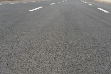 Wide asphalt road pavement and white paint line low angle view background