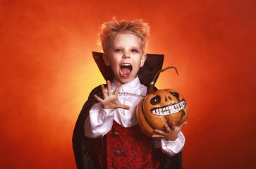happy child boy in costumes of vampire  in dark red background in halloween