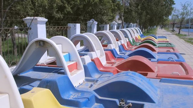 Colored catamarans on the waterfront near the sea along the fence. Catamaran rental. Catamarans travel boat for tourism vacation. Catamarans river and sea water transport.