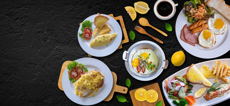 Breakfast full food in restaurant,  coffee,Eggs, Cheese, Bread, Salmon Steak,woodspoon,slud, Sliced ​​Lemon Placed in a white tile palette on a black granite table, top view.