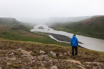 Iceland hiking concept. Single unidentified male traveler standing on the hill near Asbyrgi, Northern Iceland. Beautiful river solitude landscape.