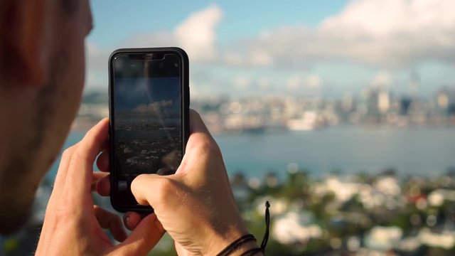 SLOWMO - Close up of caucasian man taking photo and refocus on Auckland skyline, New Zealand