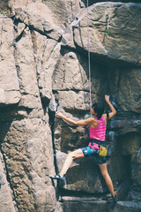 The girl climbs the granite rock.