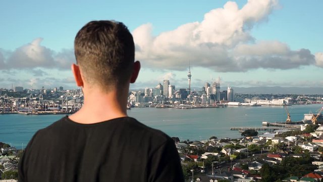 Young caucasian man looking at Auckland skyline from Devonport, New Zealand