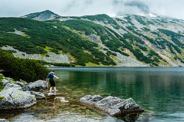 Young man try a water in Beautiful lake in Tatra mountains. Poland