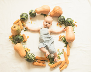 Cute baby lies in a circle of autumn harvest