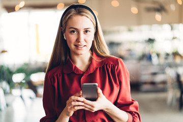 Portrait of handsome woman with mobile phone in hands standing in open space