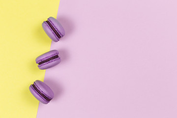 Three french macarons on a yellow and purple background. Place for text.
