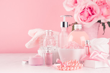 Modern girlish dressing table with pink cosmetics products, accessories and roses bouquet on soft white wood table.