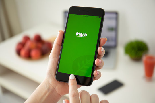 Woman holding iPhone 8 plus with Internet store iHerb