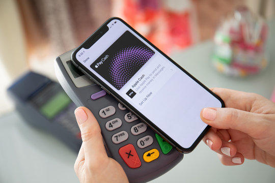 Woman holding iPhone with Apple Pay Cash and online terminal.