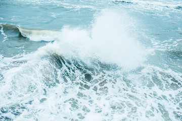 Obraz premium Waves Breaking and Spraying at High Seas and Strong Winds. Storm at the sea in autumn cloudy rainy day.
