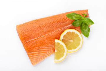 Fresh raw salmon fillets with herbs and lemon isolated on white background.
