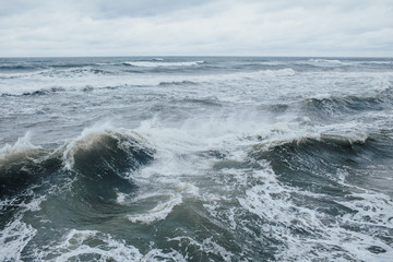 Waves Breaking and Spraying at High Seas and Strong Winds. Storm at the sea in autumn cloudy rainy...