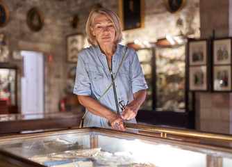 Woman visitor in the historical museum looking at art object.