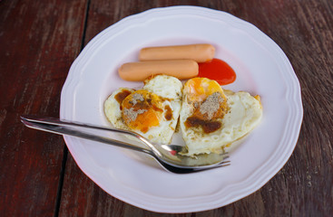 Boiled sausage and Fried eggs with white dish on the wood table