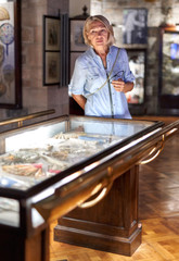 Woman visitor in the historical museum looking at art object.