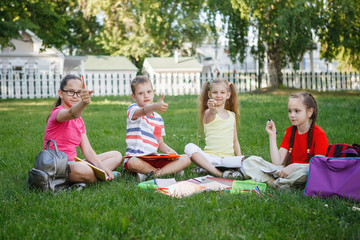 Four children sitting on the green grass.