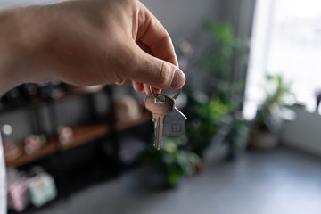 Fototapeta premium Concept of renting an apartment. House key in man hands. Young woman. Modern light lobby interior. Real estate, hypothec, moving home or renting property.