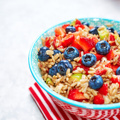 healthy oatmeal with fruits and berries, strawberries, blueberries and figs in a blue bowl on a gray background for Breakfast