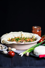 meat pie with carrots, onions and cheese in a baking dish on a dark background