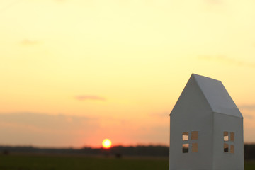 mock up of a white paper house on a sunset background. window view planning