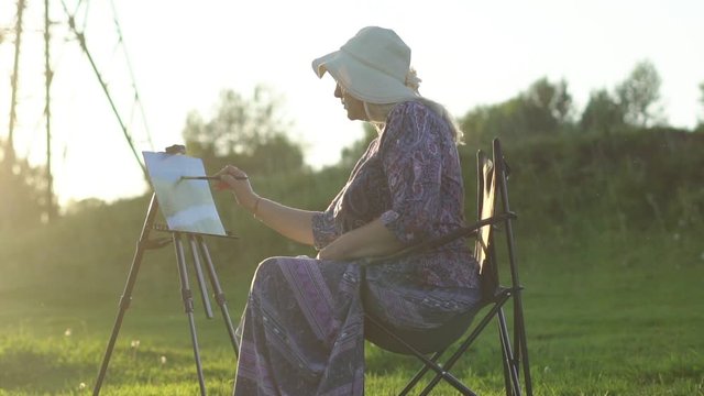 an elderly woman draws in nature