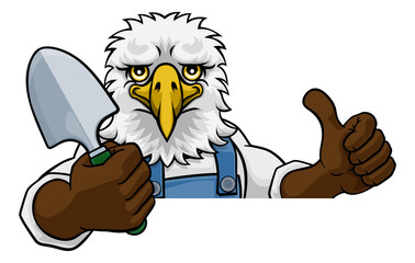 An eagle gardener cartoon gardening animal mascot holding a garden spade tool peeking round a sign and giving a thumbs up