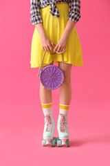 Beautiful young woman on roller skates against color background