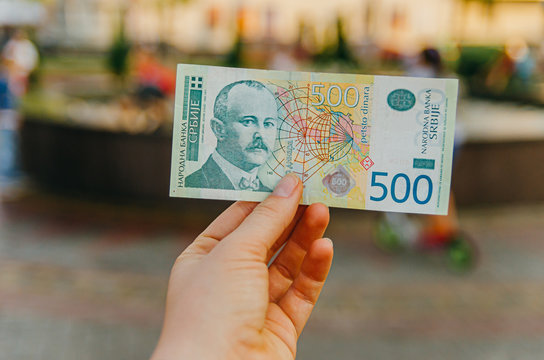 female hand holds a banknote of 500 (five hundred) Serbian dinars on a street in the city.