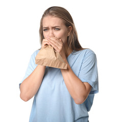 Woman with paper bag having panic attack on white background