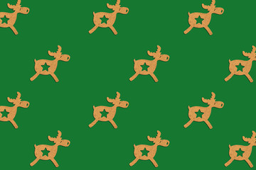 Wooden Christmas toy Deer is lined with a pattern on a green isolated background. Merry Christmas and Happy New Year concept. Minimalistic style. Flat lay, top view