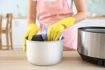 Woman cleaning modern multi cooker in kitchen