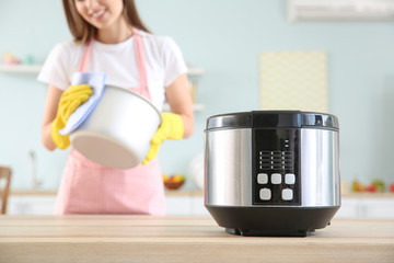 Woman cleaning modern multi cooker in kitchen