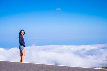 Dreaming and  freedom concept with beautiful tall standing young woman with closed eyes and clouds and blue sky in background